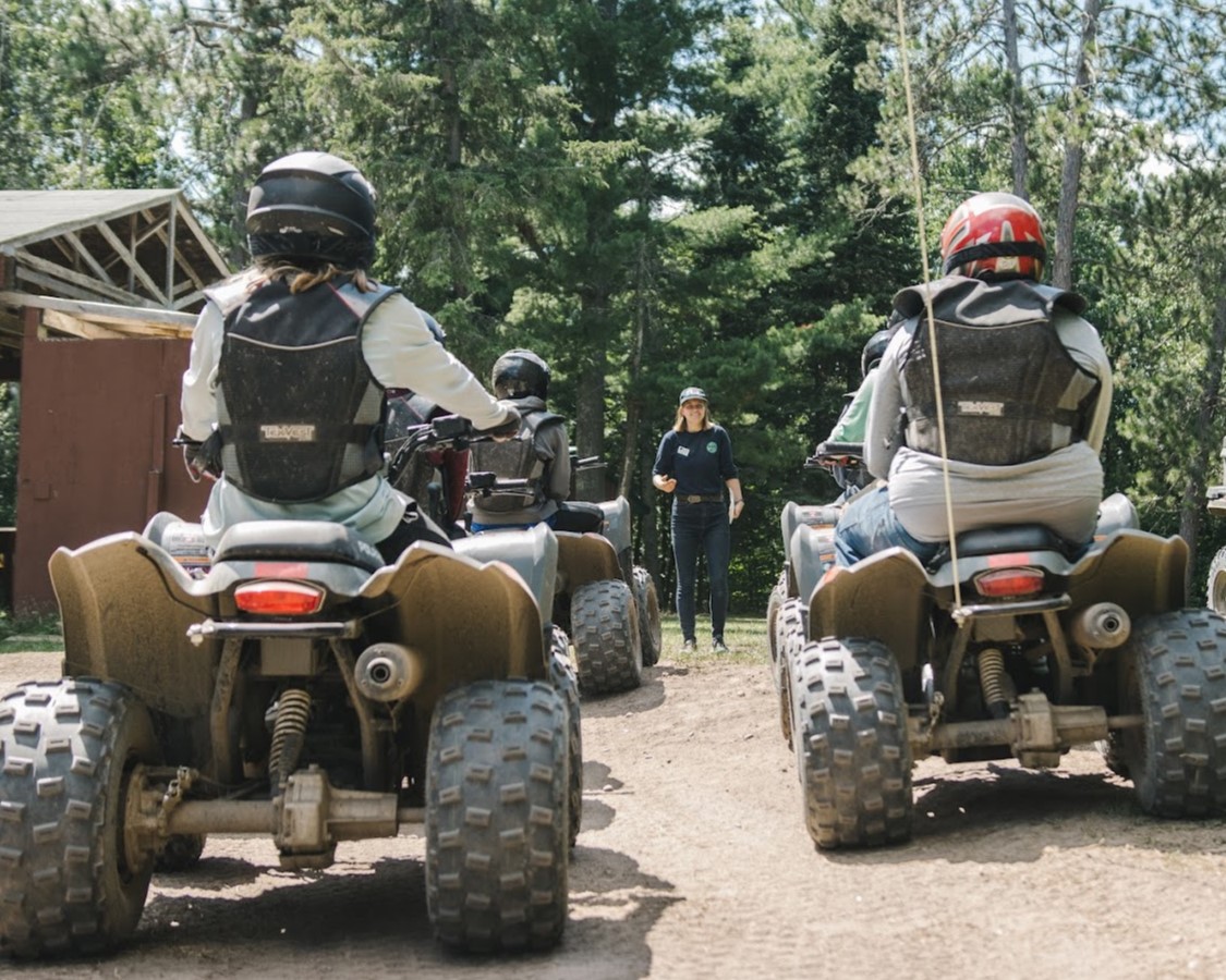 4 Scouts in full protective gear on ATVs in two lines looking at their instructor