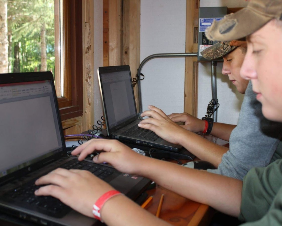 Two Scouts are working typing up a Script on the computer.