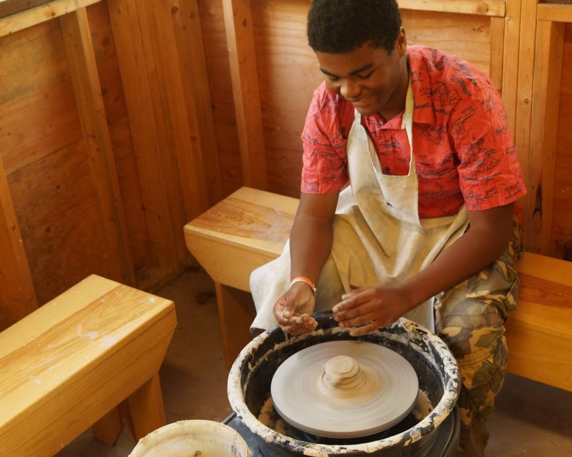 A Scout spinning a piece of clay on the wheel